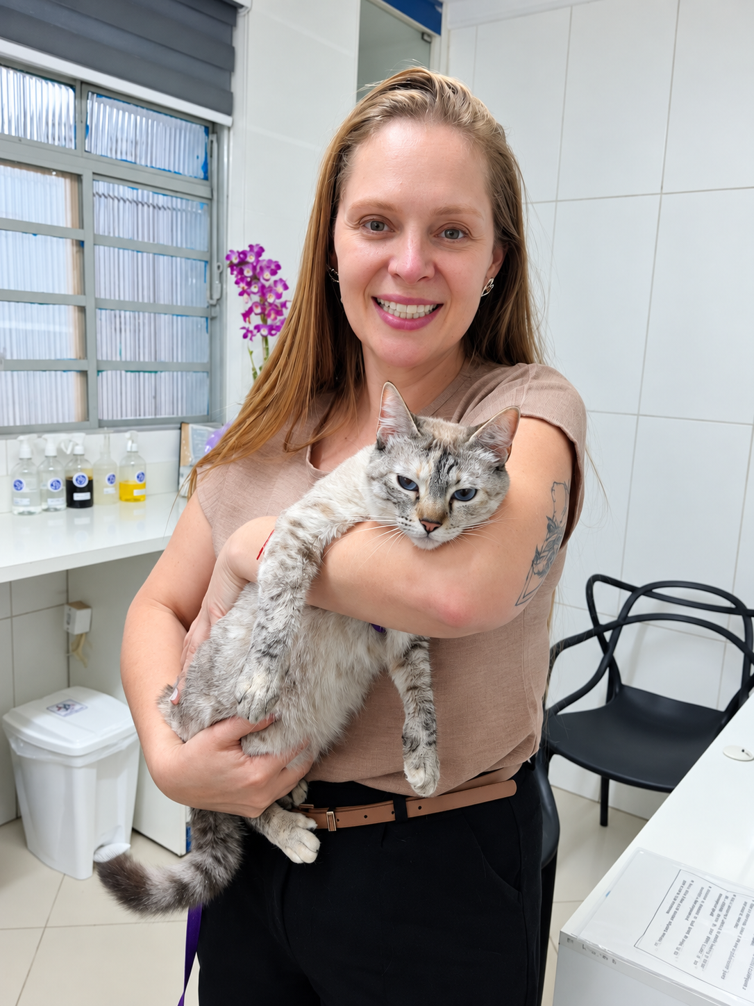 Veterinária da Clínica Veterinária Alfa segurando um gato no consultório